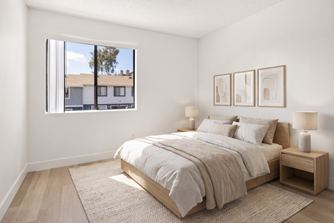 A bedroom with a large bed and a window overlooking a building.
