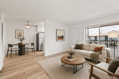 A living room with a white couch, a coffee table, and a dining table with chairs.