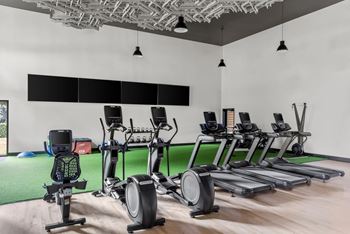 A gym with a row of treadmills and elliptical machines.