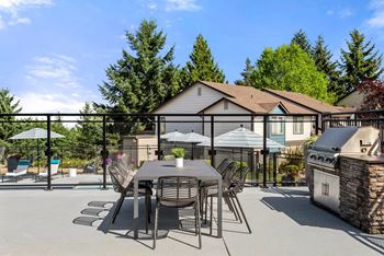 A patio with a table and chairs is surrounded by trees.