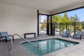 A small pool in a room with a glass door leading outside.