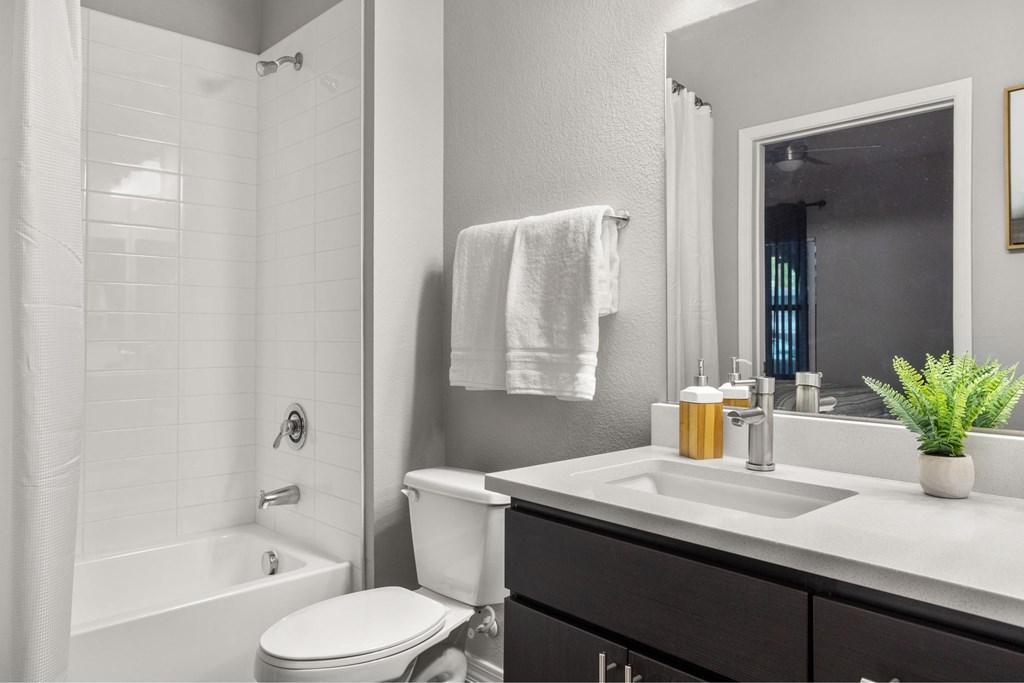 A white towel hangs on a wall above a white sink in a bathroom.
