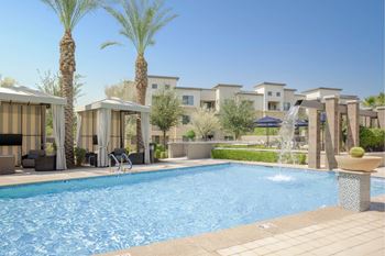 A pool surrounded by palm trees and lounge chairs.