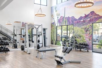 A gym with a variety of equipment and a large window showing a view of the outdoors.