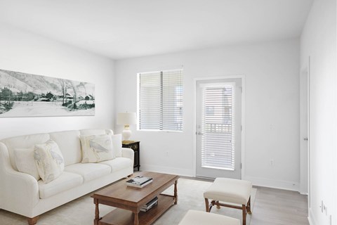 A living room with a white couch, a coffee table, and a painting on the wall.