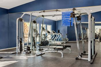 A gym with a variety of equipment including treadmills, weights, and exercise machines.