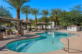 A pool surrounded by palm trees and a gazebo.