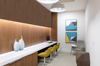 A room with a white desk, yellow chairs, and a brown wall.