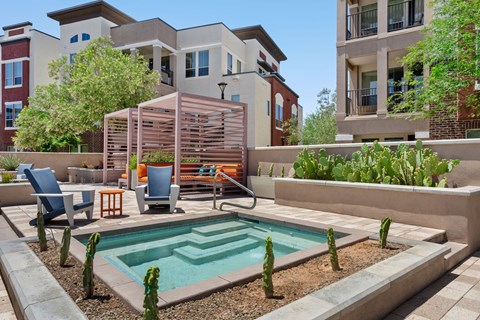 A pool surrounded by a patio with chairs and a table.