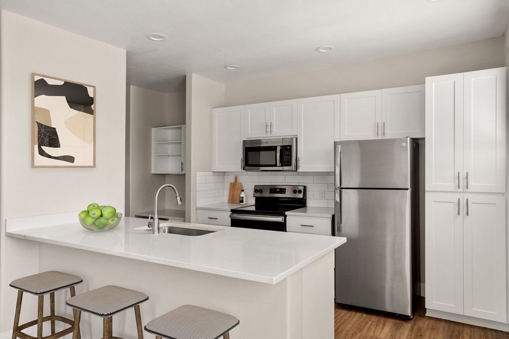 A modern kitchen with white cabinets and stainless steel appliances.