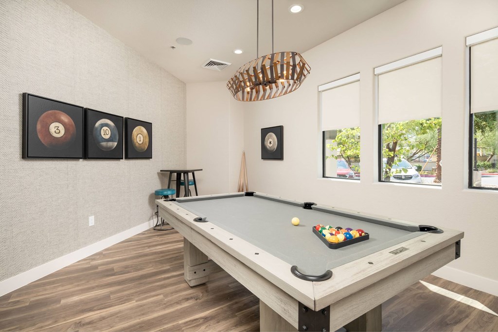 A pool table with a green cloth and white balls is in the center of the room.