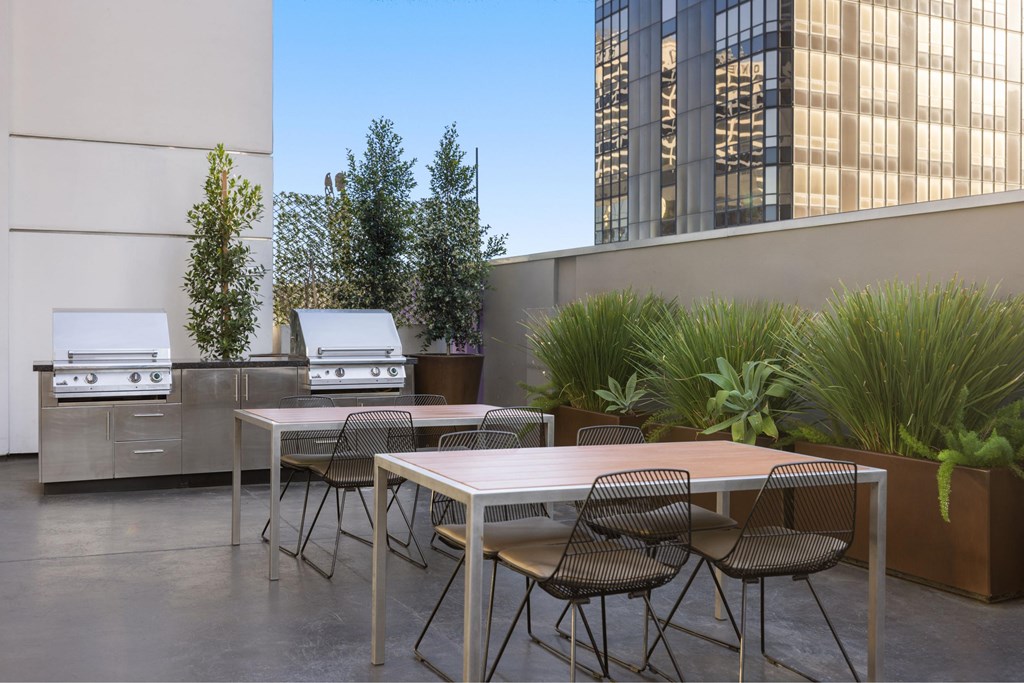 A patio with a table and chairs and a grill.
