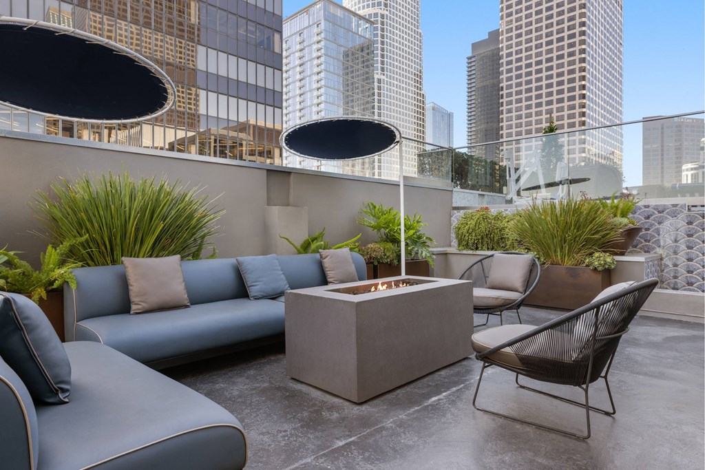 A patio with a couch, chair, and table with a view of the city.