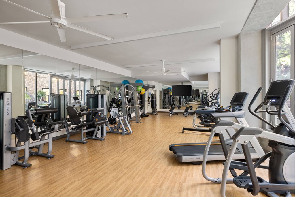A gym with a variety of equipment including treadmills, weights, and exercise machines.