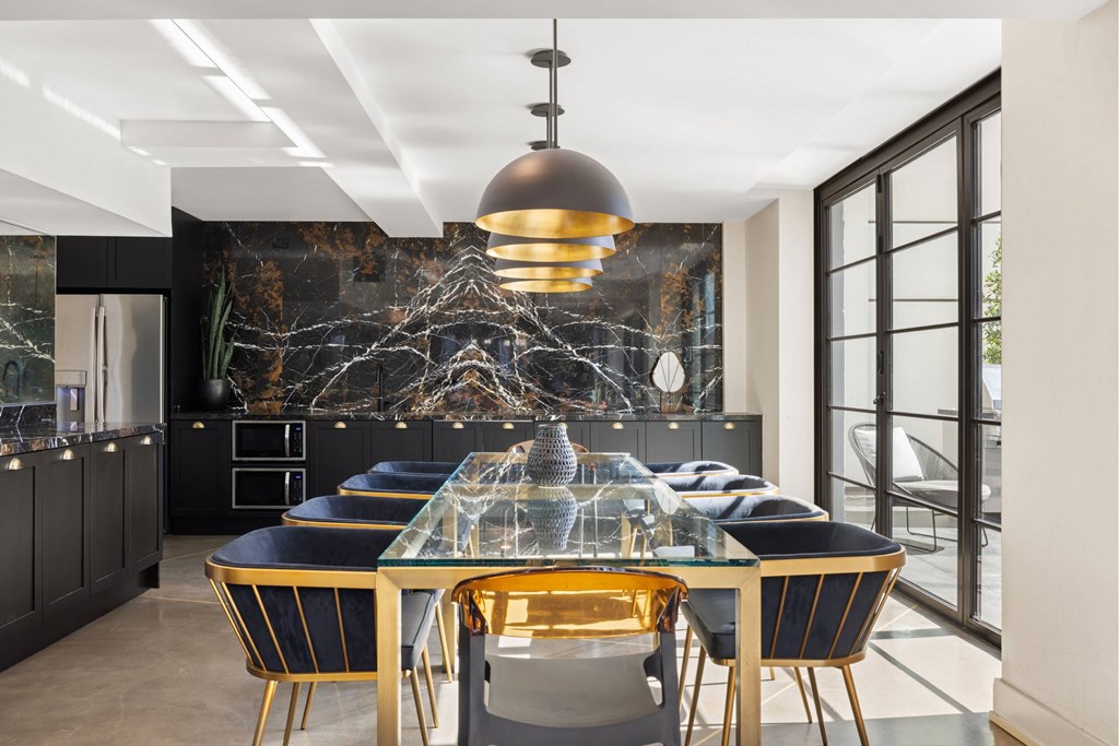A modern dining room with a glass table and black and gold chairs.