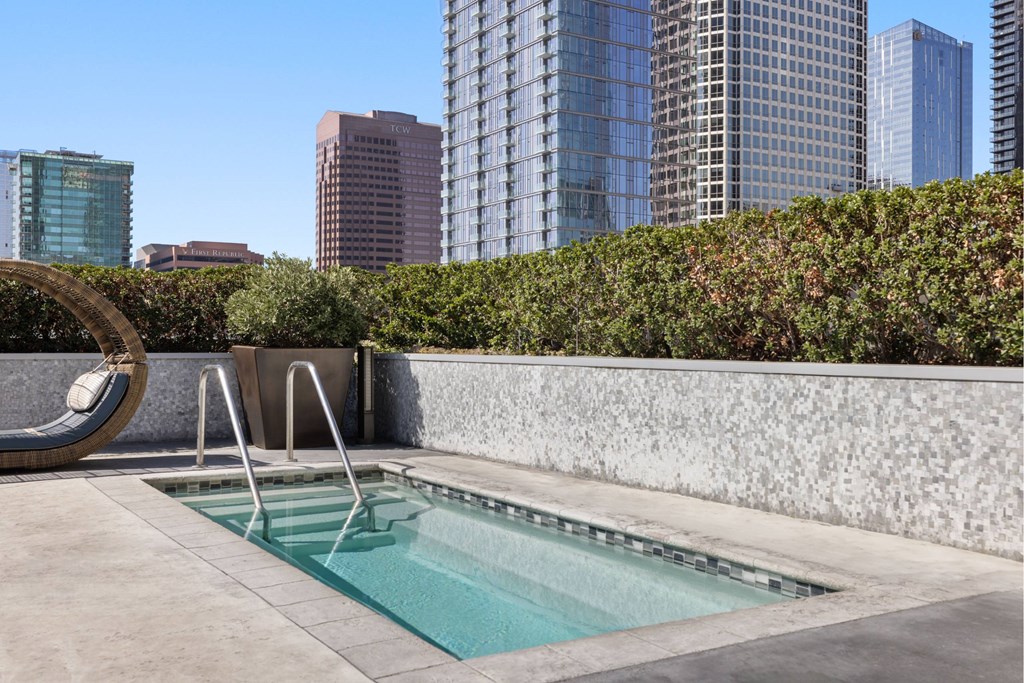 A small pool with a chair and a wall in the foreground with a cityscape in the background.