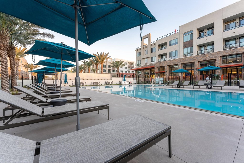 A pool area with sun loungers and umbrellas.