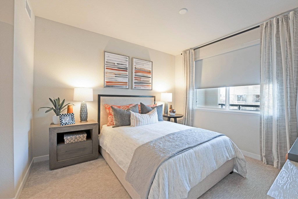 A bedroom with a large bed and a window with curtains.