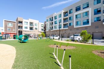 A playground with a slide and swings is surrounded by apartment buildings.