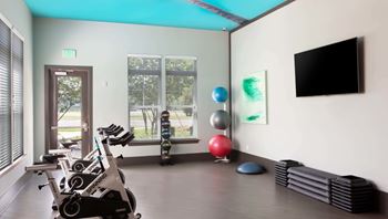A gym with exercise equipment and a television.