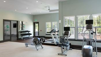 A gym with a variety of equipment including treadmills, weights, and exercise machines.