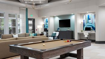A pool table is in the middle of a room with a couch and a television.