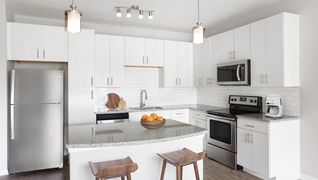A modern kitchen with white cabinets and stainless steel appliances.