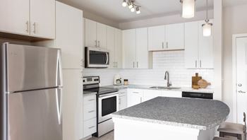 A kitchen with white cabinets and a stainless steel refrigerator.