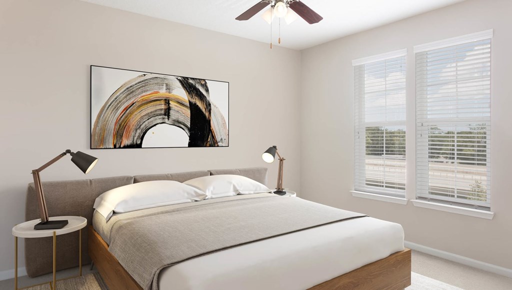 A bedroom with a large bed, a ceiling fan, and a painting on the wall.