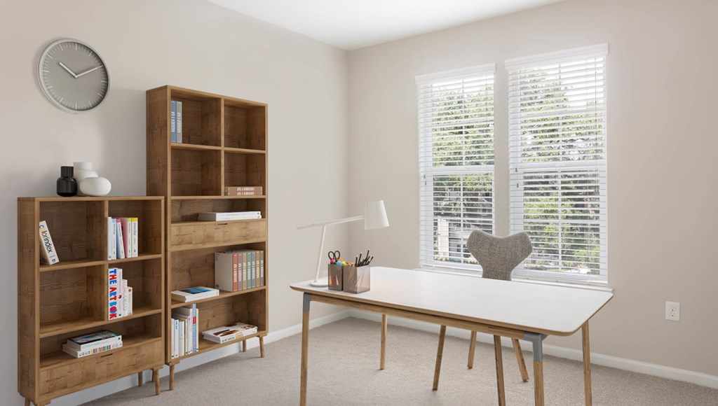 A room with a table, a bookshelf, and a window with blinds.