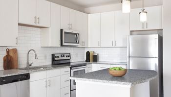 A kitchen with a bowl of apples on the counter.