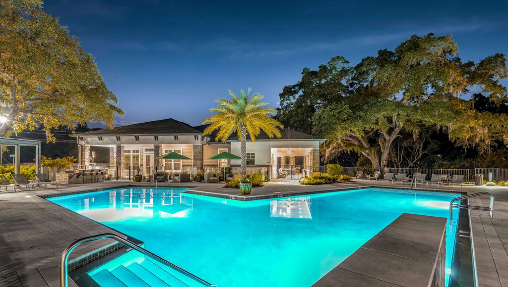 A large swimming pool in front of a building with trees around it.