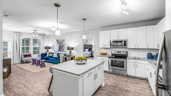 A modern kitchen with a large island and a dining area with a sofa and chairs.