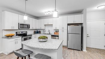 A kitchen with a marble island and stainless steel appliances.