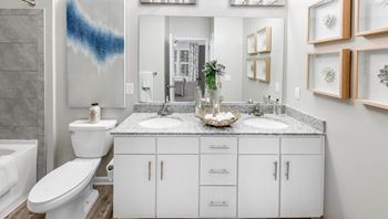 A bathroom with a white toilet, sink, and cabinets.