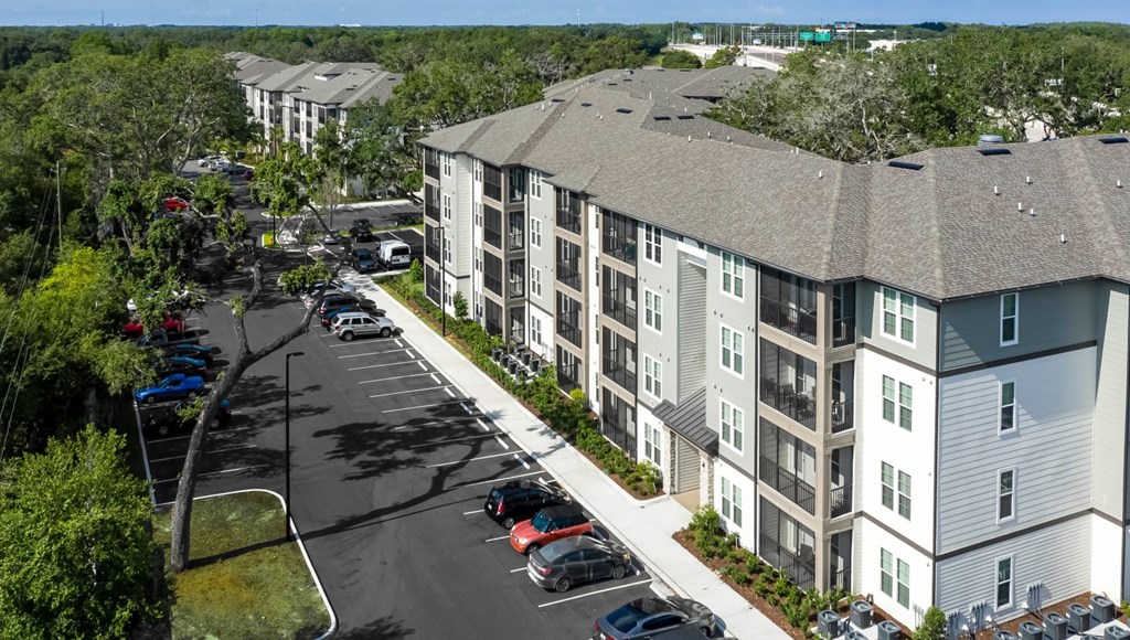 A parking lot in front of a building with cars parked.
