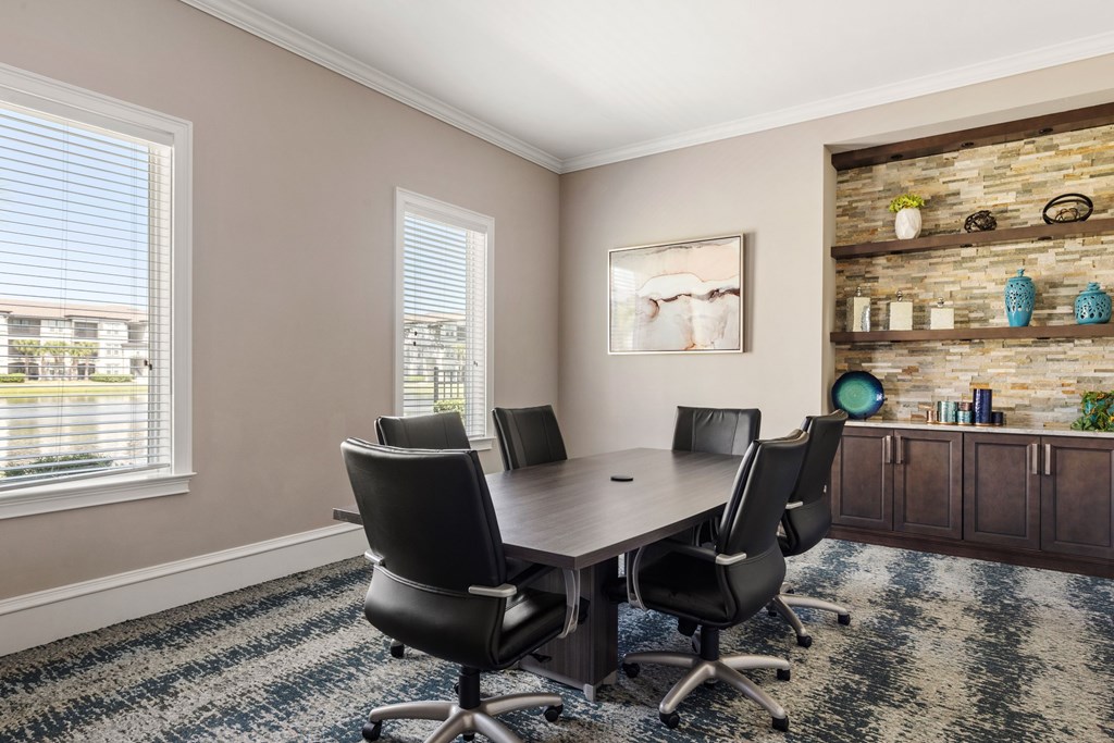 A conference room with a stone wall and a table with four chairs.
