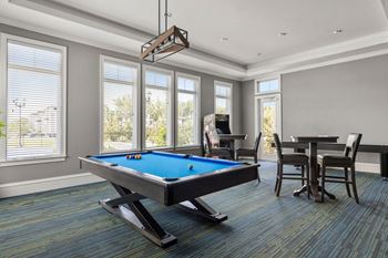 A pool table in a room with a chair and a dining table.