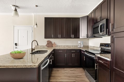 A kitchen with dark brown cabinets and a granite countertop.