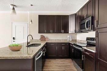 A kitchen with dark brown cabinets and a granite countertop.