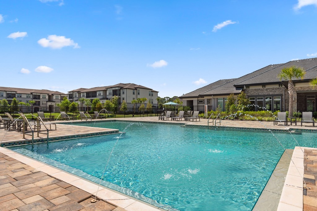 A large swimming pool with a fountain in the middle and chairs around it.