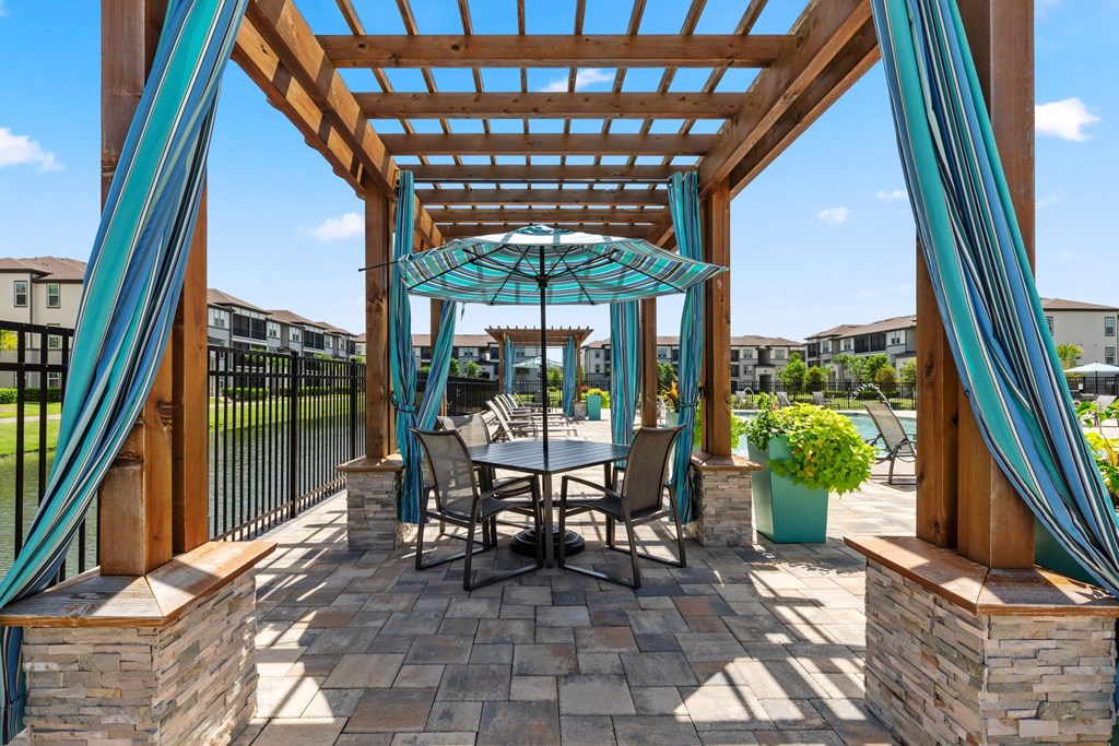 A patio with a table and chairs under a wooden pergola.