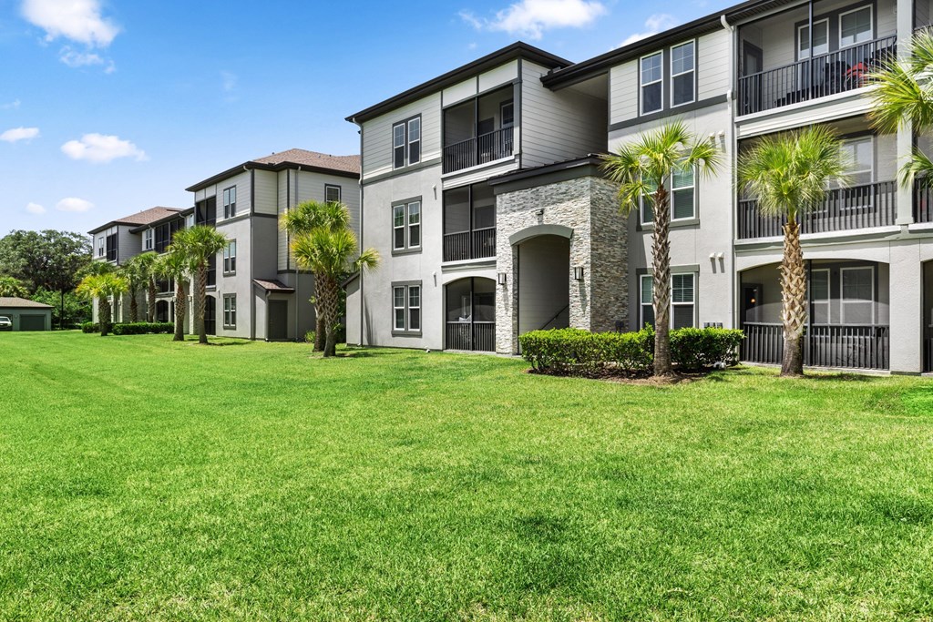 A row of apartment buildings with green lawns in front.