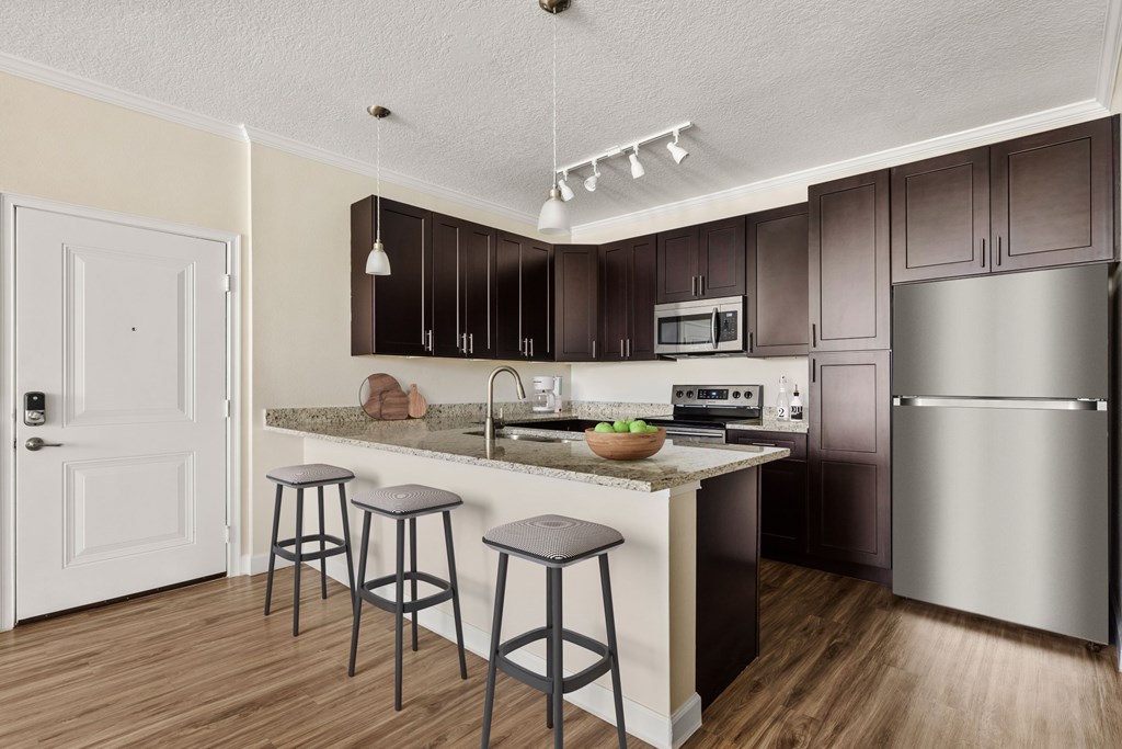 A kitchen with a white door and a counter with a bowl of fruit on it.