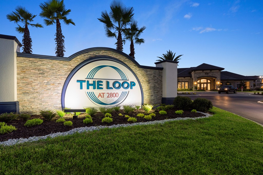 The entrance to The Loop at 2800 with a sign and palm trees.