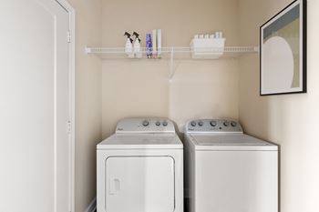 Two white front loading washing machines in a laundry room.