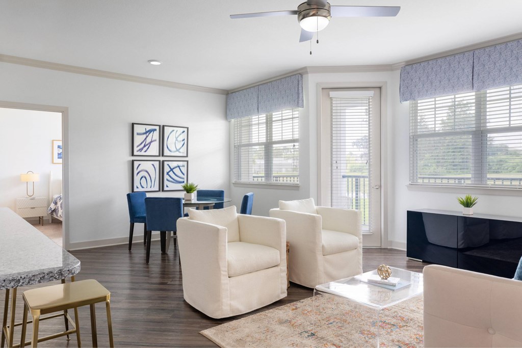A living room with a white ceiling fan and a rug on the floor.