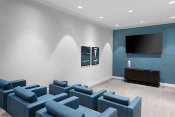 A room with blue couches and a flat screen TV mounted on the wall.