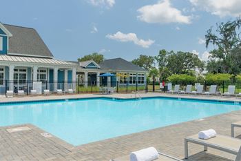 A swimming pool surrounded by lounge chairs and a building with blue trim.
