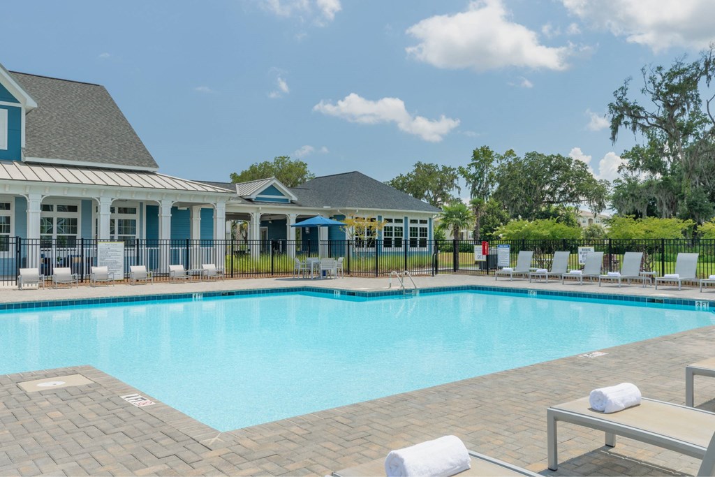 A swimming pool surrounded by lounge chairs and a building with blue trim.